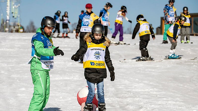 En ledare i en skidbacke hjälper barn att åka slalom. Foto: Ulf Palm.